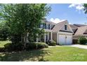 Classic two-story home featuring a covered porch, black shutters, attached two-car garage, and a lush front yard at 10792 Elsfield Nw Ave, Concord, NC 28027