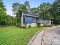 A stylish two-story home with blue accents and gray brickwork is nestled in a lush landscape at 1261 Westbrook Cir, Gastonia, NC 28052