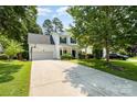 Lovely two-story home with driveway, lush green lawn, and mature trees creating a serene setting at 16121 Wrights Ferry Rd, Charlotte, NC 28278