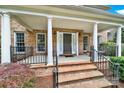 Inviting front porch with brick steps, white columns, iron railing, and a dark-stained front door at 16714 Hammock Creek Pl, Charlotte, NC 28278