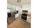 Well-lit kitchen with white cabinets, stainless steel fridge and range, and modern flooring at 2412 Elizabeth Ave, Shelby, NC 28150