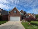 Two-story brick home with attached two car garage, beautiful landscaping, and driveway at 2563 Firethorn Ct, Gastonia, NC 28056