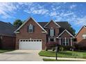 Charming two-story brick home with an attached two car garage, beautiful landscaping and a blue sky at 2563 Firethorn Ct, Gastonia, NC 28056
