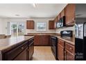 Bright kitchen featuring dark wood cabinetry, black appliances, and a view to the outdoors through sliding glass doors at 3512 Gibbon Terrace Ct, Charlotte, NC 28269