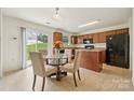 Cozy kitchen and dining area with wood cabinets, a kitchen island, and a view to the outdoors through sliding glass doors at 3512 Gibbon Terrace Ct, Charlotte, NC 28269
