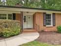 Close-up of a red brick home featuring a white front door and neatly trimmed landscaping at 4000 Chandworth Rd, Charlotte, NC 28210