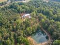 Aerial view of red barn style home with surrounding acreage and pond at 574 Crescent Rd, Rockwell, NC 28138