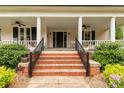 Inviting front porch features classic columns and is adorned with beautiful plants and a charming swing at 7 Kings Mountain St, York, SC 29745