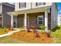 Inviting home showcasing a stone-accented facade, covered porch, and well-maintained front yard at 700 Windage Way, Pineville, NC 28134