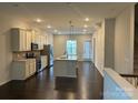 Open concept kitchen with stainless steel appliances, kitchen island and dark hardwood floors throughout at 9236 Ainslie Downs St, Charlotte, NC 28273