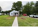 Charming single-story home with a well-maintained lawn, walkway, front porch, and flag at 410 Gann St, Lowell, NC 28098