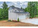 Gray two-story home with two-car garage and covered front porch, set among trees at 126 Meadow Glen Dr, Troutman, NC 28166