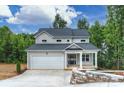Inviting gray two-story house showcasing a covered porch, landscaping and two-car garage at 126 Meadow Glen Dr, Troutman, NC 28166