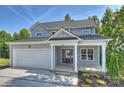 Beautiful gray home with two car garage, inviting front porch, and landscaped garden bed at 126 Meadow Glen Dr, Troutman, NC 28166