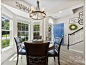 Bright dining room with a round wood table, view of the blue front door, and stairs to the upper level at 1644 Backcreek Ln, Gastonia, NC 28054