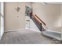 Spacious living room with high ceilings, staircase, and neutral carpet at 3826 Yorkford Dr, Charlotte, NC 28269