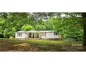 Cozy one-story home showcasing a covered porch, red shutters, and a lush green yard with mature trees at 6140 Barclay Ln, Clover, SC 29710