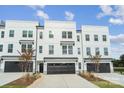 New construction three-story townhome with black garage doors, stone accents, and a concrete driveway at 9214 Delancey Ln # 62, Concord, NC 28027
