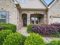 Stone-accented entryway with a covered porch and lush landscaping at 1004 Fairbanks Ct, Indian Trail, NC 28079