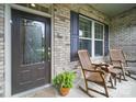 Inviting front porch with rocking chairs, a charming door, and brick accents at 1004 Fairbanks Ct, Indian Trail, NC 28079