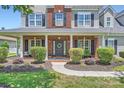 Close-up view of the home's entrance featuring a brick porch, elegant front door with wreath, and manicured landscaping at 113 Dairy Farm Rd, Mooresville, NC 28115