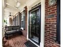 Inviting front porch featuring brick flooring, black bench, and classic ceiling fan for relaxation at 139 Harper Lee St, Davidson, NC 28036