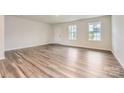Bright living room featuring beautiful flooring, fresh paint, large windows, and an exterior door to the backyard at 1545 Cottage Creek Dr, Bessemer City, NC 28016