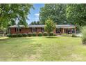 Traditional brick ranch featuring a covered porch, manicured lawn, and symmetrically planted bushes at 240 China Grove Rd, China Grove, NC 28123