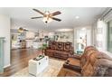 Open-concept living space with hardwood floors, ceiling fans, and an adjacent kitchen with a granite countertop island at 240 China Grove Rd, China Grove, NC 28123
