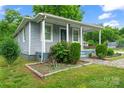 Cozy home with a quaint front porch and blue door, complemented by lush landscaping at 3400 Reid Ave, Charlotte, NC 28208