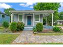 Inviting home with a quaint front porch, complemented by verdant landscaping and a stone walkway at 3400 Reid Ave, Charlotte, NC 28208