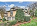 Side view of a tan home featuring an attached garage and beautiful landscaping at 5721 Ballinard Ln, Charlotte, NC 28277