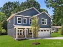 Inviting two-story home with a covered porch, an attached garage, and lush green lawn at 737 Oak St, Charlotte, NC 28214