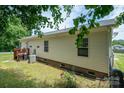 View of the side exterior, showing the house siding, an air conditioning unit, and partial deck at 792 Carolina Mill Cir, Lincolnton, NC 28092