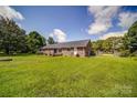 Expansive backyard with a lush lawn, mature trees, and a brick home with patio at 801 Witmore Rd, Wingate, NC 28174