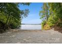 A sandy beach surrounded by a lush green forest and lake access, offering tranquility and natural beauty at 9184 Greenwood Rd, Terrell, NC 28682