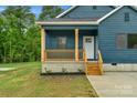 Cozy covered front porch with natural wood posts and steps to enter the home at 105 Churchill Dr, Kings Mountain, NC 28086