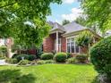 Charming brick home with lush front yard landscaping and a welcoming entrance framed by mature trees at 15929 Northstone Dr, Huntersville, NC 28078