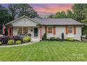 Lovely home boasts a green lawn, neat garden beds and classic architecture and covered front porch at 1621 Brookdale Ave, Charlotte, NC 28210