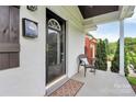 Close-up of the front porch featuring a black front door, chair, and a welcome mat at 2421 Shamrock Dr, Charlotte, NC 28205
