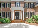 View of the front entrance with columns, a dark-colored door, and brick stairs with potted plants at 2516 Selwyn Ave, Charlotte, NC 28209