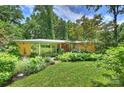 Well-maintained mid-century home features a brick facade, large windows, mature trees, and a manicured lawn at 2600 Cloister Dr, Charlotte, NC 28211