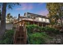 Charming multi-story home with wooden deck, stairs, and lush landscaping, creating a serene and inviting atmosphere at 29049 Snapper Pt, Tega Cay, SC 29708