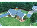 Overhead view of brick home with a well-kept lawn, mature trees, long driveway and wooden shed at 4646 River Run Cir, Hickory, NC 28602
