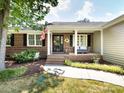 Inviting front porch with brick steps, cozy seating, and charming details like an American flag at 4925 Cedar Forest Dr, Charlotte, NC 28226