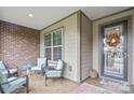 Inviting front porch with comfortable seating and a decorative wreath on the glass front door at 499 Granite Lake Ct, Denver, NC 28037