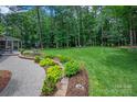 Expansive backyard featuring lush landscaping, a stone walkway, and mature trees at 516 Amanda Dr, Weddington, NC 28104