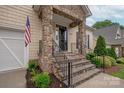 Detailed stone porch with iron railings leads to the front door, enhanced by manicured landscaping at 5917 Bridger Ct, Charlotte, NC 28211