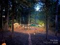 Inviting backyard with string lights, shed, and a cozy fire pit area surrounded by lush trees at 8217 Lansford Rd, Charlotte, NC 28277