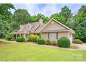 Charming tan home featuring a covered front porch and beautifully manicured landscaping at 8622 Lower Rocky River Rd, Concord, NC 28025